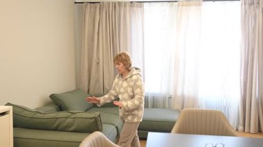 Oturma odasını temizleyen pijamalı, olgun, beyaz bir kadın.