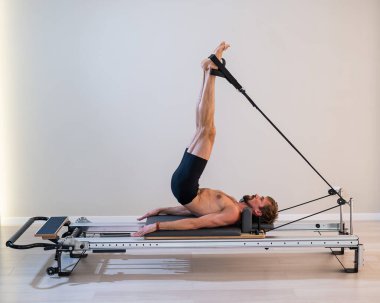 Reformcu üzerinde pilates yapan bir adam.