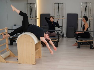 Pilates yapan üç kadın ve pilates yapan bir fıçı.