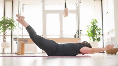Şişman kadın stüdyoda yoga yapıyor.