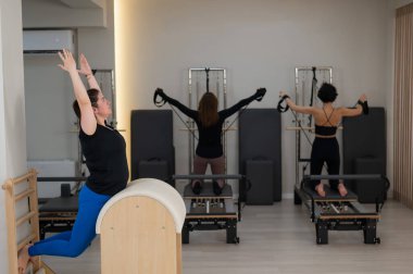 Pilates yapan üç kadın ve pilates yapan bir fıçı.