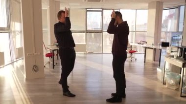 Ofiste işaret diliyle iletişim kuran iki beyaz adam.