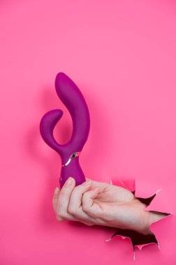 Pembe kağıttan yapılmış ahududulu seks oyuncağıyla takılan bir kadın eli.