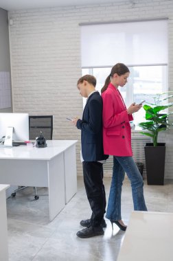 İki meslektaş sırt sırta verip akıllı telefon kullanıyor.