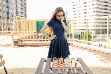 Beyaz kadın dışarıda satranç oynuyor.