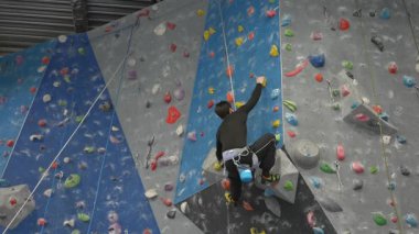 Beyaz adam tırmanma duvarında eğitim görüyor.