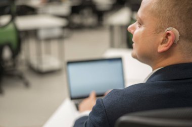 Ofiste dizüstü bilgisayarda yazan beyaz sağır adam.