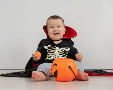 Beyaz arka planda şeker sepeti tutan Dracula Cadılar Bayramı kostümlü beyaz tatlı çocuk.