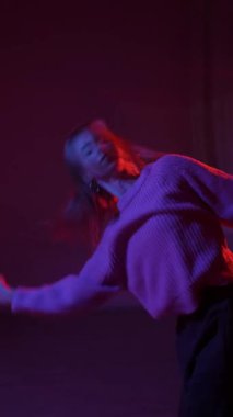 A young woman dances contemporary dances in blue and red light. Long exposure. Vertical video