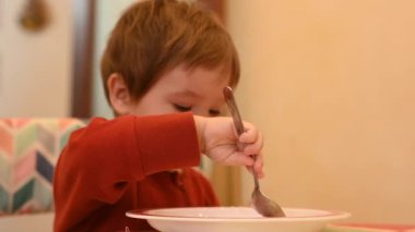 Şirin bir çocuk tek başına yulaf lapası yiyor.