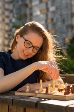Beyaz kadın dışarıda satranç oynuyor.