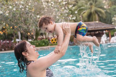 Beyaz kadın tatilde havuzda yüzerken oğlunu kucağına aldı