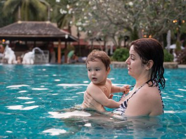 Beyaz kadın tatilde havuzda yüzerken oğlunu kucağına aldı