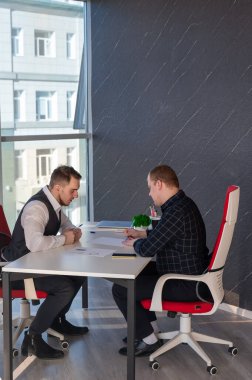 İki beyaz adam bir iş toplantısında iletişim kuruyor.