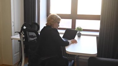 Yaşlı, ciddi bir iş kadını dizüstü bilgisayarda çalışıyor.