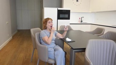 Yaşlı beyaz bir kadın makyajını mendille temizliyor.