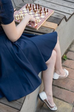 Beyaz kadın dışarıda satranç oynuyor.