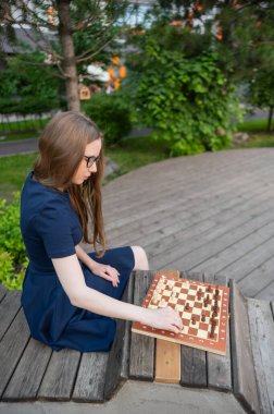 Beyaz kadın dışarıda satranç oynuyor.