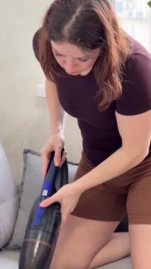 Beyaz kadın tekstil kanepesini süpürüyor. Dikey video