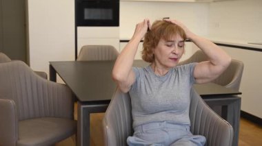 Saçlarını tarayan yaşlı beyaz bir kadın.