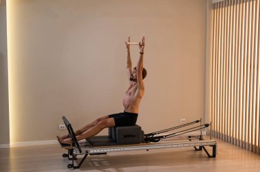 Reformcu üzerinde pilates yapan bir adam.