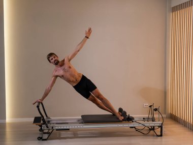 Reformcu üzerinde pilates yapan bir adam.