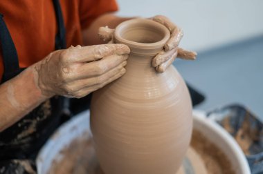 Çömlekçi elleriyle çömlekçi çarkında seramik vazo yaparken.
