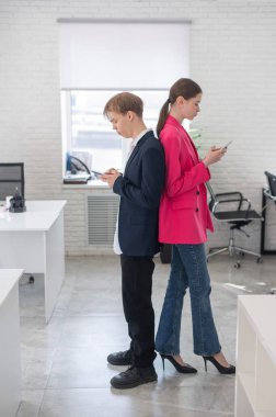 İki meslektaş sırt sırta verip akıllı telefon kullanıyor.