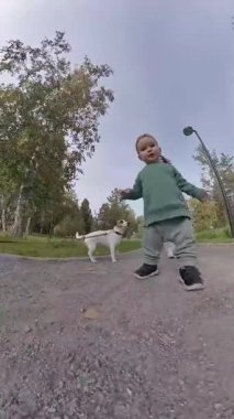 Komik çocuk annesiyle yürürken kamerayı yakalamak için koşuyor ve kollarını açıyor. Dikey video