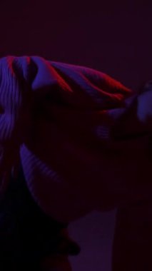 A young woman dances contemporary dances in blue and red light. Long exposure. Vertical video