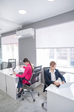 Kafkasyalı genç kadın ve erkek kendi masalarında çalışıyorlar.