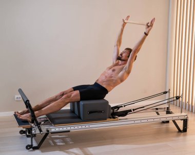 Reformcu üzerinde pilates yapan bir adam.