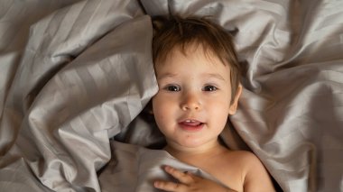 Beyaz tenli şirin bir çocuğun yatakta yatışının üst görüntüsü.