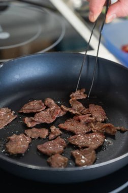Şef kızartma tavasında dana eti kızartıyor.