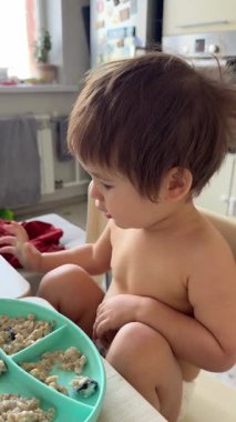 Babam bir yaşındaki çocuğunu kaşıkla yulaf lapasıyla besliyor.