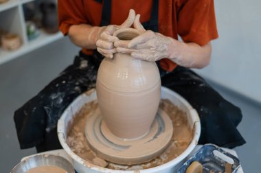 Çömlekçi elleriyle çömlekçi çarkında seramik vazo yaparken.