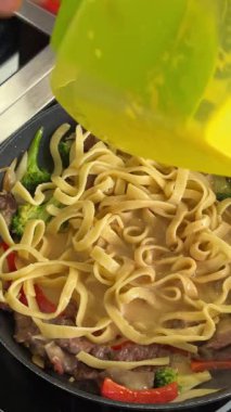 Şef tavada makarna pişirir.