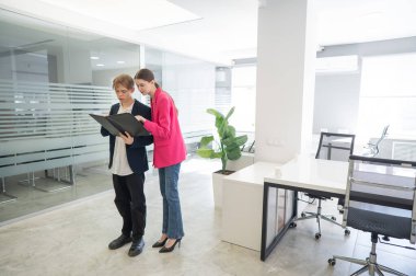 Meslektaşlar belgeli bir klasöre bakar ve iş konularını tartışırlar