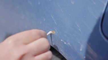 Bir adam, bir araba cesedindeki paslı bir çiziği gizliyor. Pas dönüştürücü