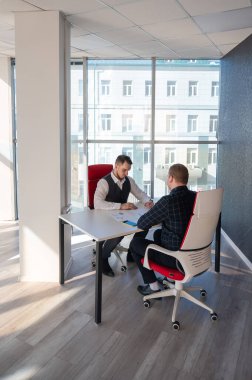 İki beyaz adam bir iş toplantısında iletişim kuruyor.