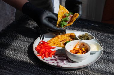 Siyah eldiven giyen bir şef fajita hazırlar.