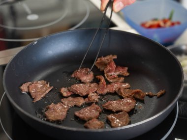 Şef kızartma tavasında dana eti kızartıyor.