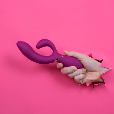 Pembe kağıttan yapılmış ahududulu seks oyuncağıyla takılan bir kadın eli.