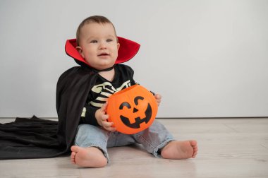 Beyaz arka planda şeker sepeti tutan Dracula Cadılar Bayramı kostümlü beyaz tatlı çocuk.