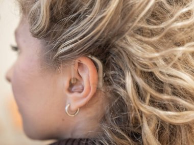 Kafkasyalı genç bir kadının kulağına yakın plan işitme cihazı takılmış.