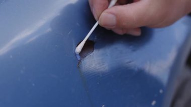 Bir adam, bir araba cesedindeki paslı bir çiziği gizliyor. Pas dönüştürücü