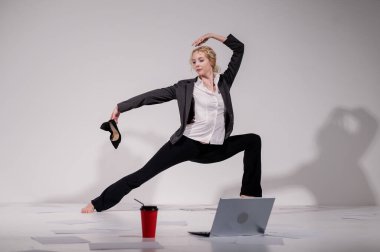 Beyaz arka planda iş elbisesiyle dans eden çıplak ayaklı balerin.