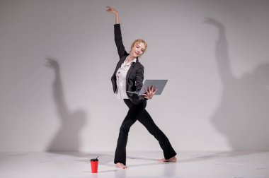 Beyaz arka planda iş elbisesiyle dans eden çıplak ayaklı balerin.