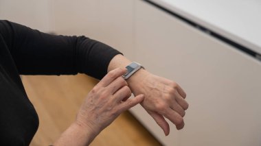 Kafkasyalı yaşlı bir kadın akıllı saate bakıyor. Ellerin yakın çekimi