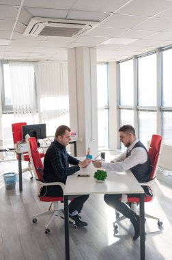 İki beyaz adam bir iş toplantısında iletişim kuruyor.